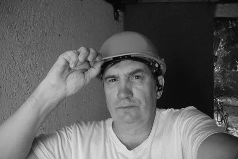 Middle-aged man in construction helmet looking forward at construction site Stock Photos