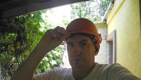 Middle-aged man in construction helmet looking forward at construction site Stock Photos