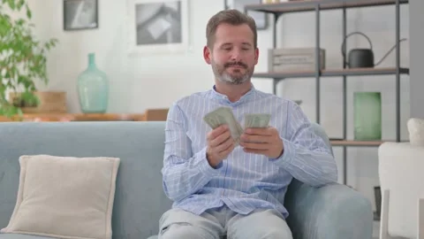 Middle Aged Man Counting Money while Sitting on Sofa at Home Video stock 287898563