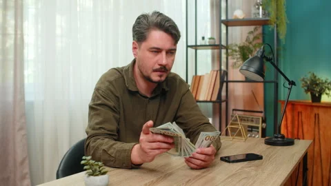 Middle-aged man counts cash smiling showing big financial success dollar bills Stock Footage 347035945