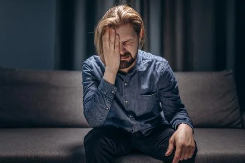 Middle-aged man crying alone at living room without lights Stock Photos