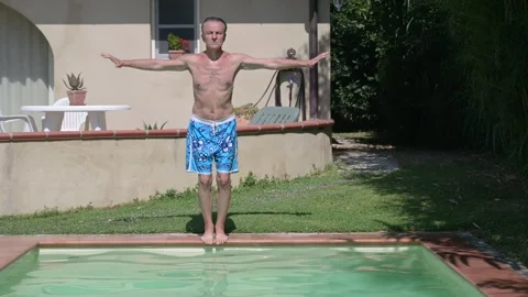 Middle-aged man dives into a swimming pool, cannonball style Stock Footage 281228010