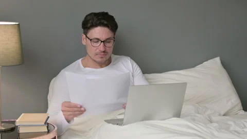 Middle Aged Man with Documents working on Laptop in Bed 스톡 동영상 142372375
