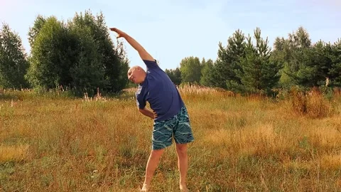A middle-aged man does physical exercises in the morning in the meadow Vidéo 158894094