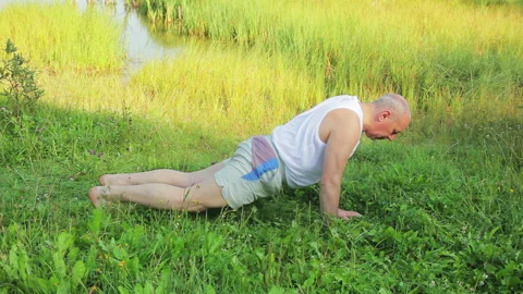 A middle-aged man does push-ups on the lake in the morning 库存影片 119996271