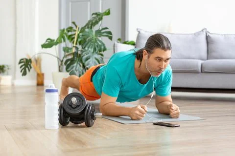 Middle-aged man doing the plank exercise. He follows the online guide via Stock-Fotos