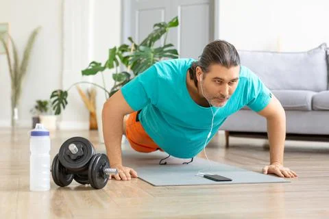 Middle-aged man doing push-ups. He uses an online tutorial from the internet to Stock Photos