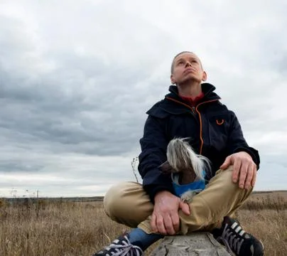 A middle-aged man dreams while looking at the sky on an autumn day in nature. Stock Photos