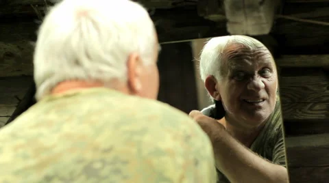 A middle aged man dressed in a khaki t-shirt, shaving his own hair with a Stock Footage 66202964