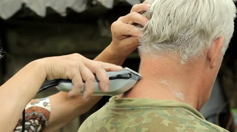 A middle aged man dressed in a khaki t-shirt, shaving by woman with a clipper Stock Footage 66202991