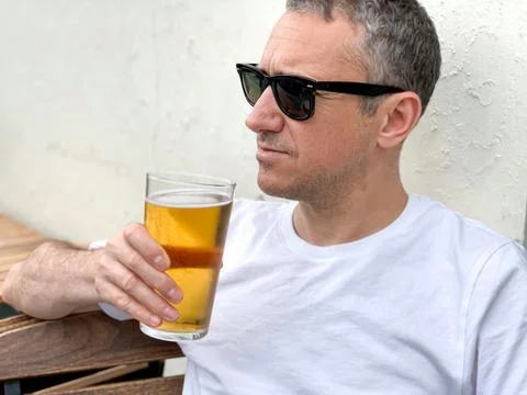 Middle aged man is drinking beer in a cafe or restaurant pub outdoor. Drinking Stock-Fotos