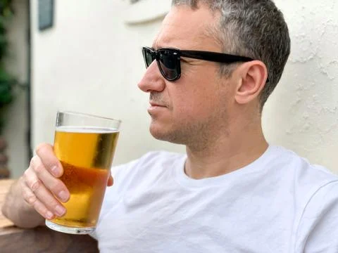 Middle aged man is drinking beer in a cafe or restaurant pub outdoor. Drinking Stock Photos