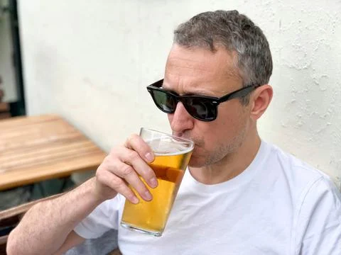 Middle aged man is drinking beer in a cafe or restaurant pub outdoor. Drinking Foto stock