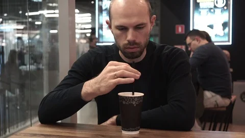 Middle-aged man drinking a coffee drink from a straw in a cafe Stock Footage 127563514