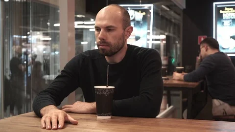 Middle-aged man drinking a coffee drink from a straw in a cafe Stock Footage 127563643