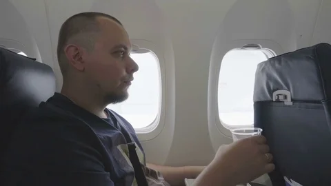 Middle-aged man drinking water in the airplane cabin . Stock Footage 81069089