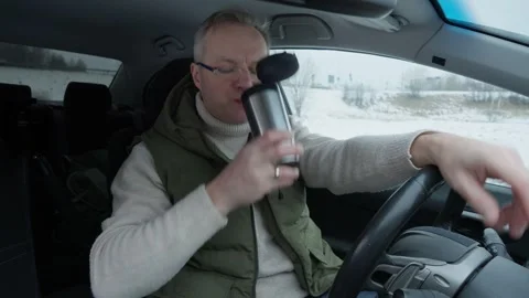 Middle-aged man eats sandwich and drinks coffee in his car Stock Footage 302907444