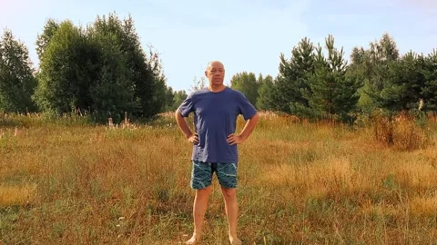 A middle-aged man is engaged in gymnastics in the morning in the meadow Vídeo Stock 160419071