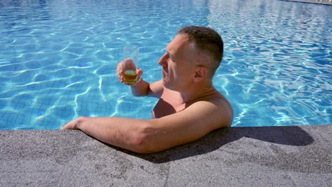 Middle-aged man enjoying a cold beer in a swimming pool Stock Footage 203952872