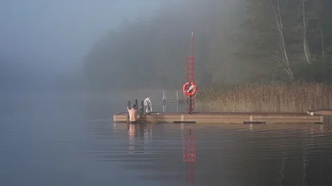 Middle aged man entering cold lake water from wooden dock Stock Footage 346604791