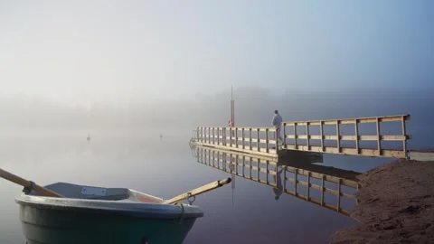 Middle aged man entering cold lake water from wooden dock Stock Footage 346613870
