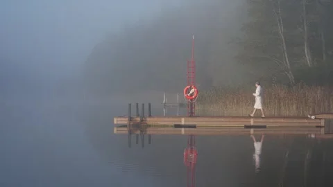 Middle aged man entering cold lake water from wooden dock Stock Footage 346614000
