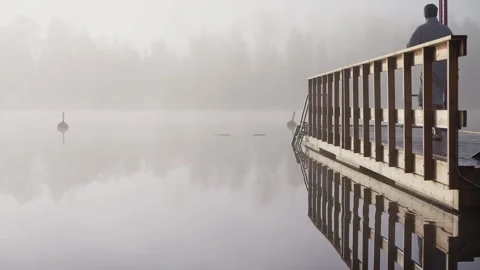 Middle aged man entering cold lake water from wooden dock Stock Footage 346614361