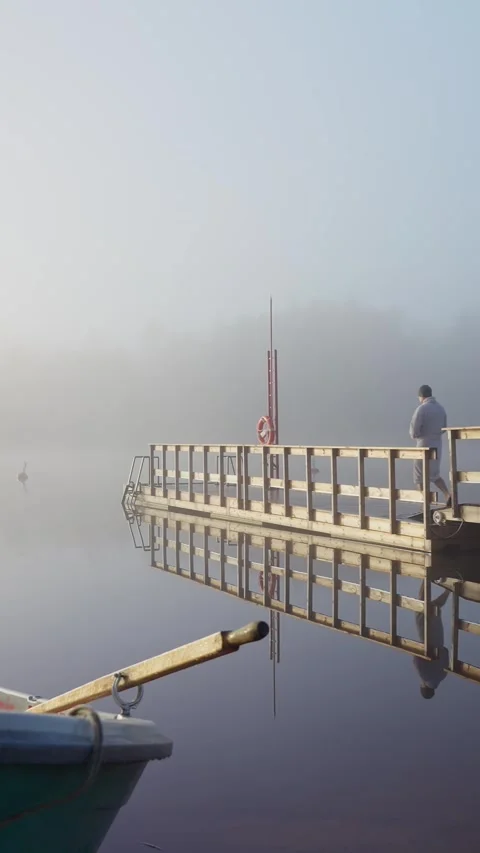 Middle aged man entering cold lake water from wooden dock Stock Footage 346614451