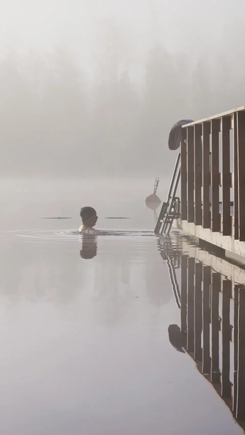 Middle aged man entering cold lake water from wooden dock Stock Footage 346614574