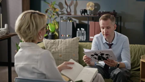 Middle Aged Man Examining Inkblot Card during Therapy Session Stock Footage 340630729