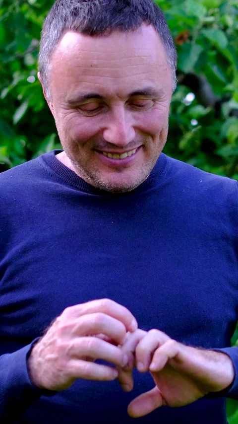 Middle aged man examining rough hands after garden work and smiling at results Stock Footage 345744525