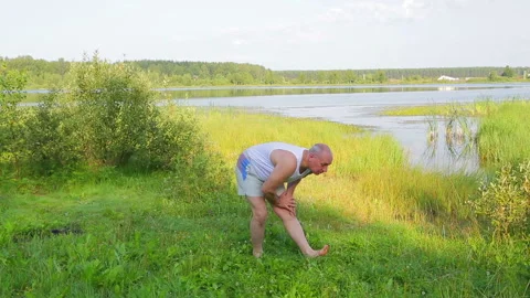 A middle-aged man exercises on the lake in the morning Stock Footage 119996216