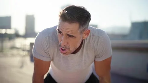 Middle-aged man exhausted after running, taking a break to breathe to continue Stock Footage 267694470