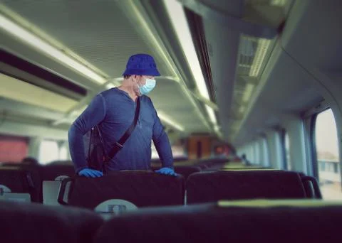 Middle aged man is finding his seat on an empty train. He wearing a face mask Stock Photos