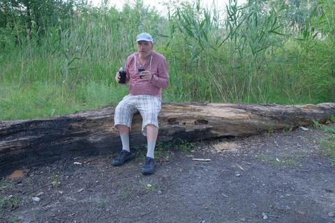 Middle-aged man in the forest walking walking tourist in checkered shorts and Stock Photos