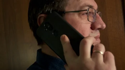 A middle-aged man with glasses takes a call on his smartphone Stock Footage 150694914