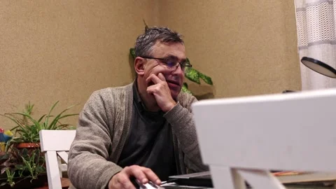 Middle-aged man with glasses using a laptop and a computer mouse at home. T.. Stock Footage 336203132