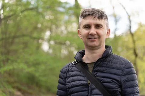 A middle-aged man with graying in a thin down jacket in early spring. Stock Photos