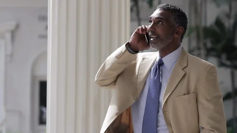 Middle-aged man greeting someone while on a phone call. 스톡 동영상 88368731