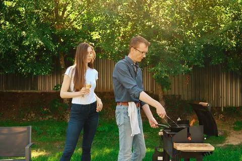 Middle-aged man grilling a steak on a grill and his daughter watching on hi.. Foto stock