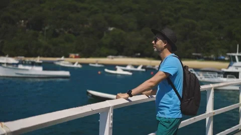 A middle-aged man in a hat and t-shirt stands contemplatively overlooking the Stock Footage 308319532