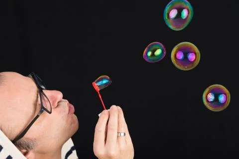 Middle aged man having fun blowing soap bubbles Stock Photos