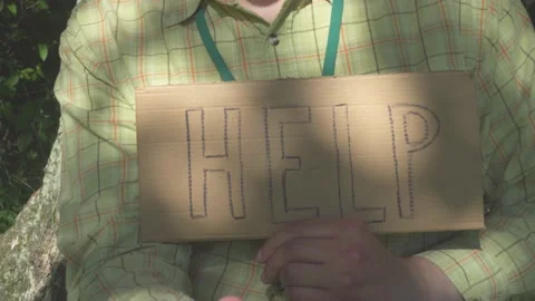 Middle-aged man with a help sign stands by the tree. HELP cardboard. Stock Footage 133701287