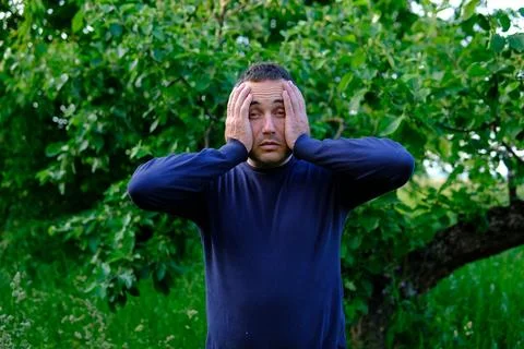Middle aged man holding head with both hands and reacting to stress fear or Stock Photos
