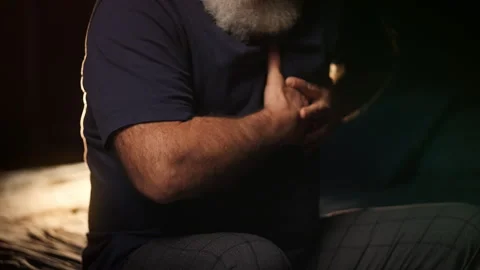 Middle-aged man holds chest while sitting on bed, heart failure warning Stock Footage 346714352