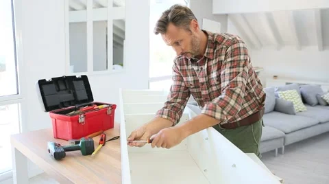 Middle-aged man at home assembling furniture parts Stock Footage 56065405