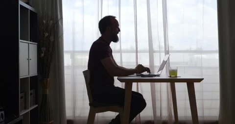 Middle-aged man at home in backlit during a video conference with his laptop Stock Footage 155276671