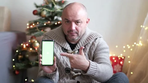 Middle aged man at home during Christmas Eve day pointing finger on the phone Video stock 165452872
