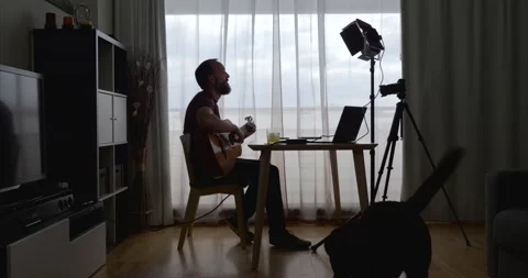 Middle-aged man interrupted by his dog while recording an online guitar cours Stock Footage 155276604