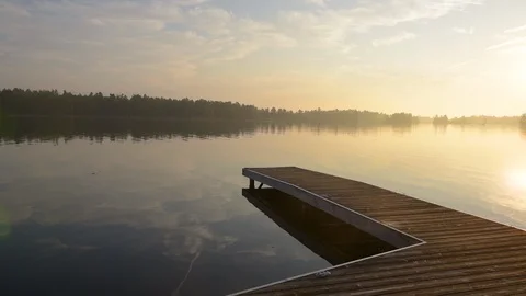 Middle aged man jumping off dock as sun rises in background.  Stock Footage 95020724